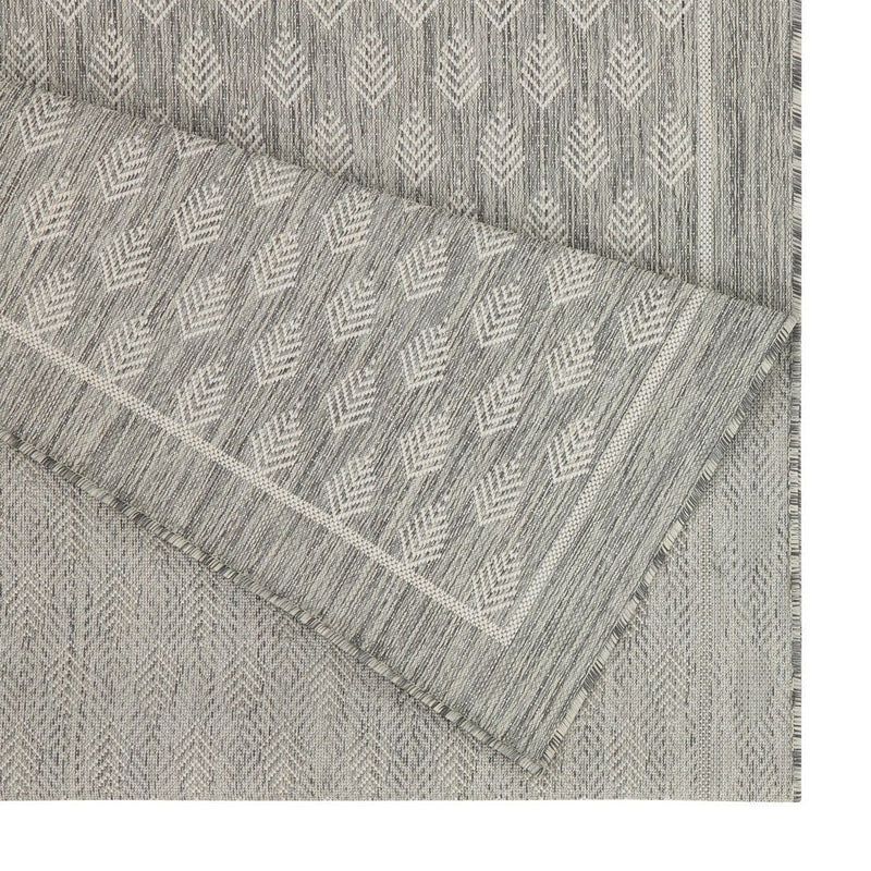 Light gray area rug with repeating diamond pattern and fringed trim edge