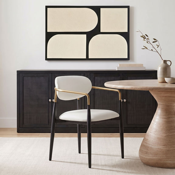 White upholstered dining arm chair with rounded back, black legs, gold arm frame