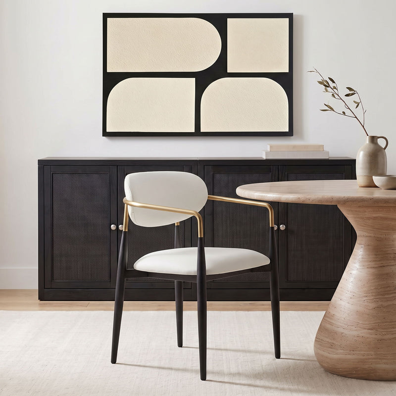 White upholstered dining arm chair with rounded back, black legs, gold arm frame