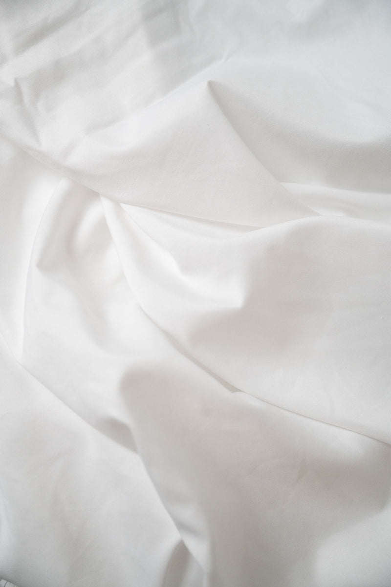 Brushed hypoallergenic sheet fabric close-up in white, soft wrinkle texture