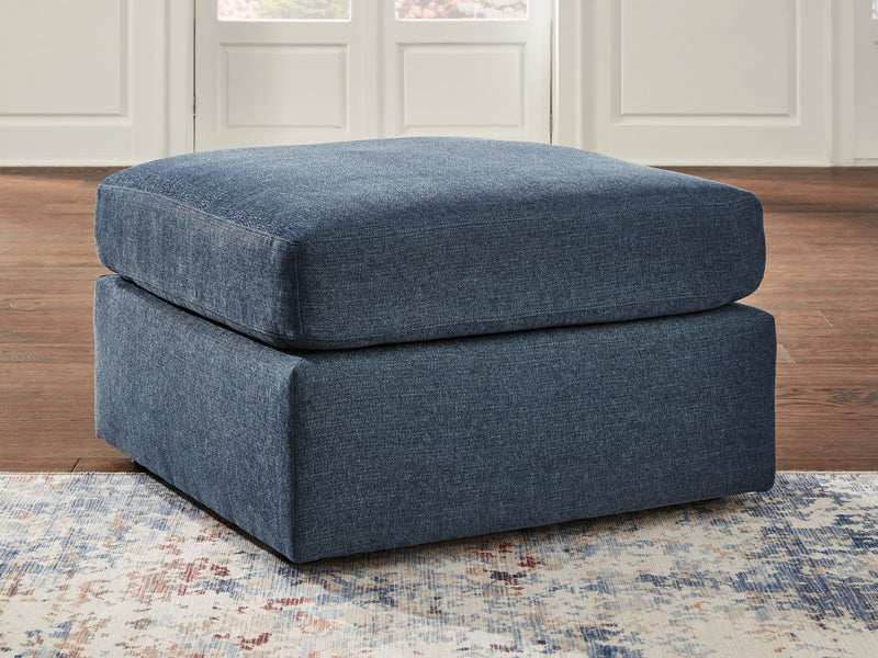 Upholstered dark blue ottoman with rounded top, side profile, and low legs