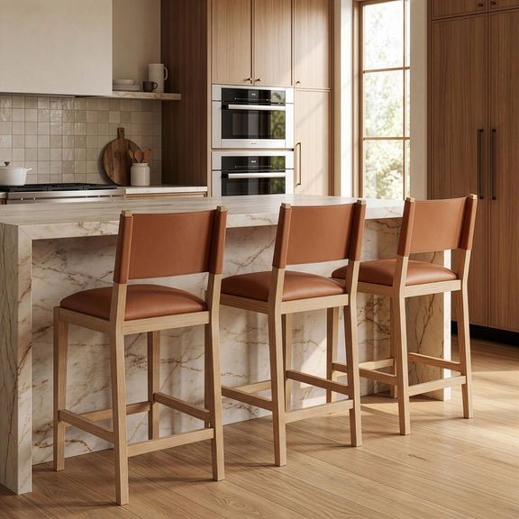 Set of light brown vegan leather counter stools with cushioned seats and wood legs