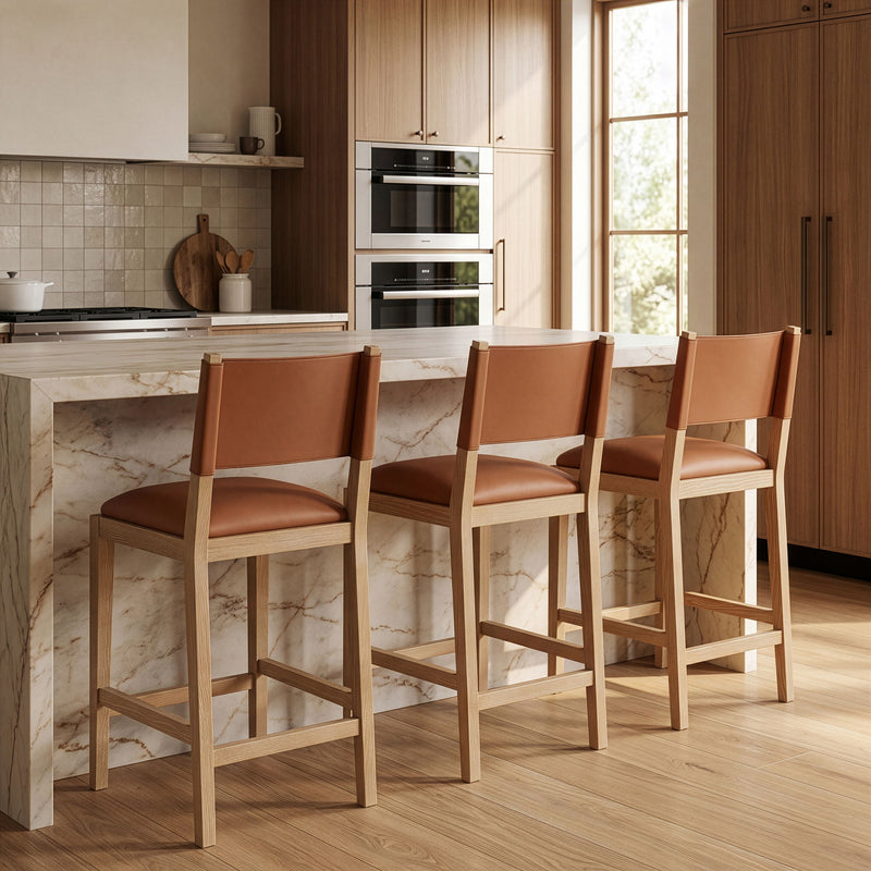 Set of light brown vegan leather counter stools with cushioned seats and wood legs