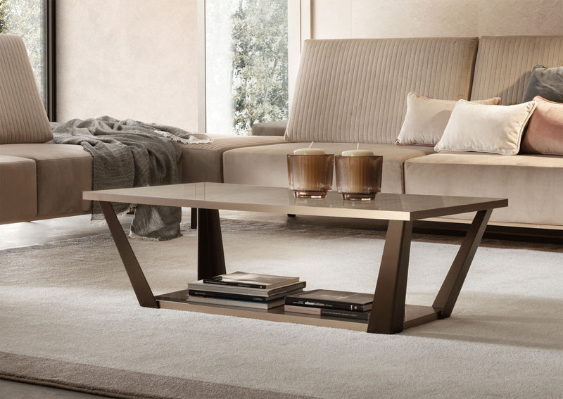 Beige coffee table with dark brown legs, open shelf, books and candle holders