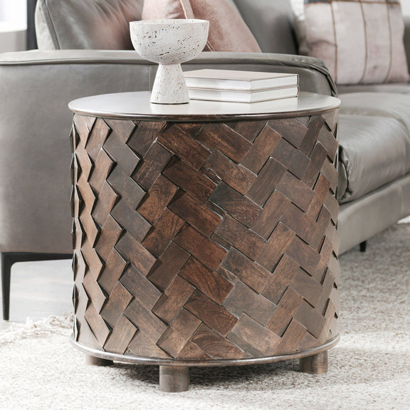 Round mango wood table with woven sides and top holding a small bowl and stacked books