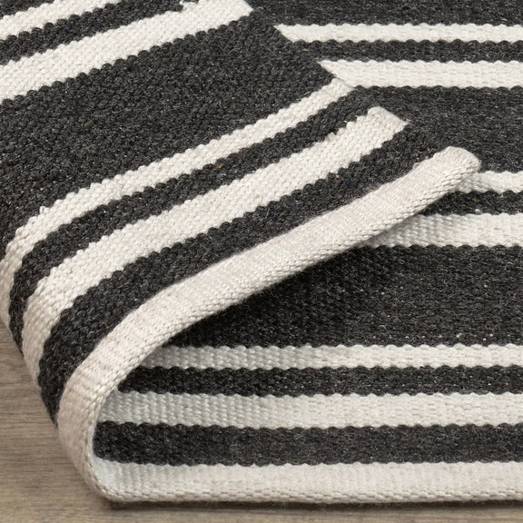 Close-up angled view of charcoal rug featuring white horizontal stripe bands