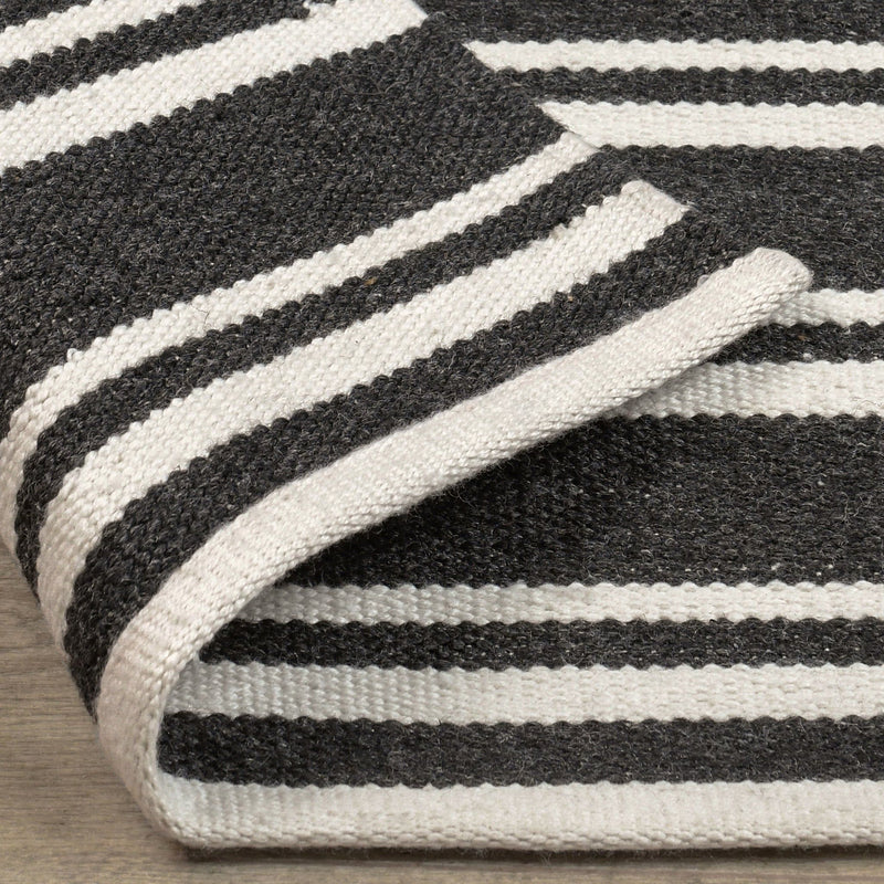 Close-up angled view of charcoal rug featuring white horizontal stripe bands