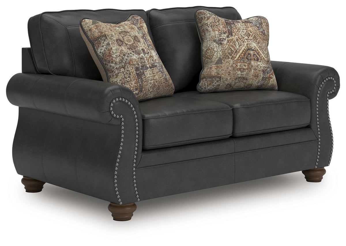 Dark gray sofa with button-tufted arm detail and two patterned throw pillows