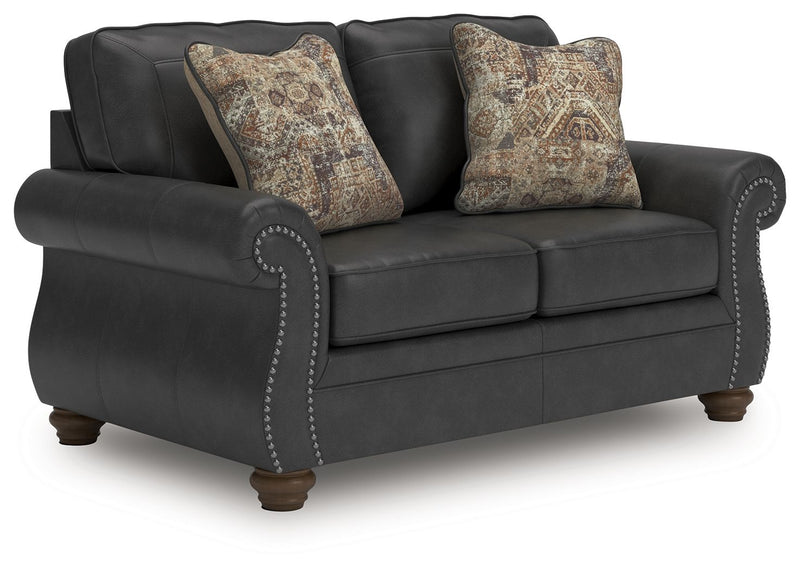 Dark gray sofa with button-tufted arm detail and two patterned throw pillows