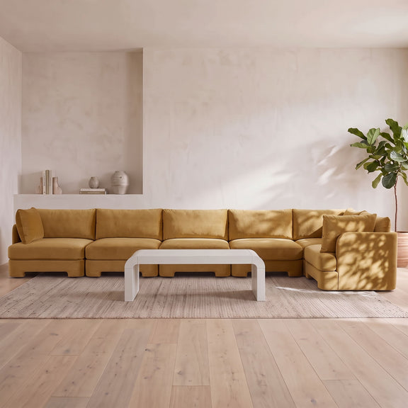 Light brown velvet L-shaped sectional sofa with wide seating and chaise-style end section.
