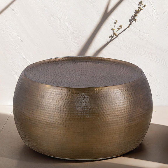 Round hammered metal coffee table with a dark top and bronze finish