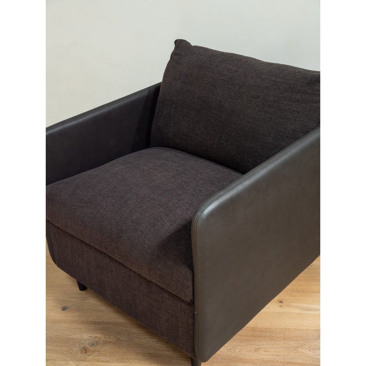 Warm black accent chair with boxy rounded frame, side view, thick seat and arm pads