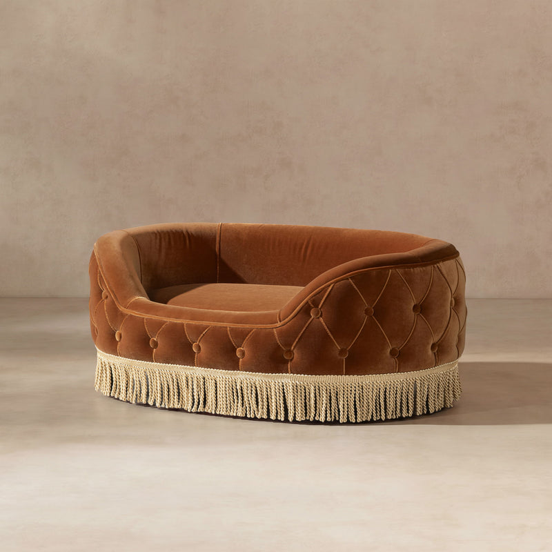 Burnt orange tufted dog sofa bed with open cushioned interior and fringed base