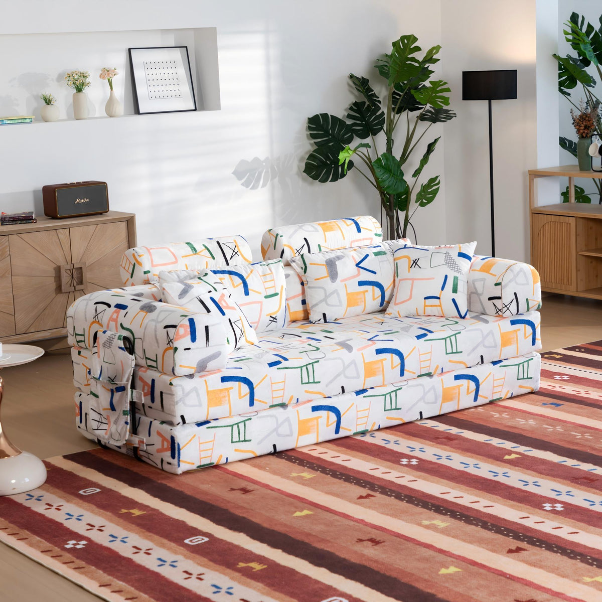 White sleeper sofa bed with colorful icon-pattern upholstery, angled view on seat
