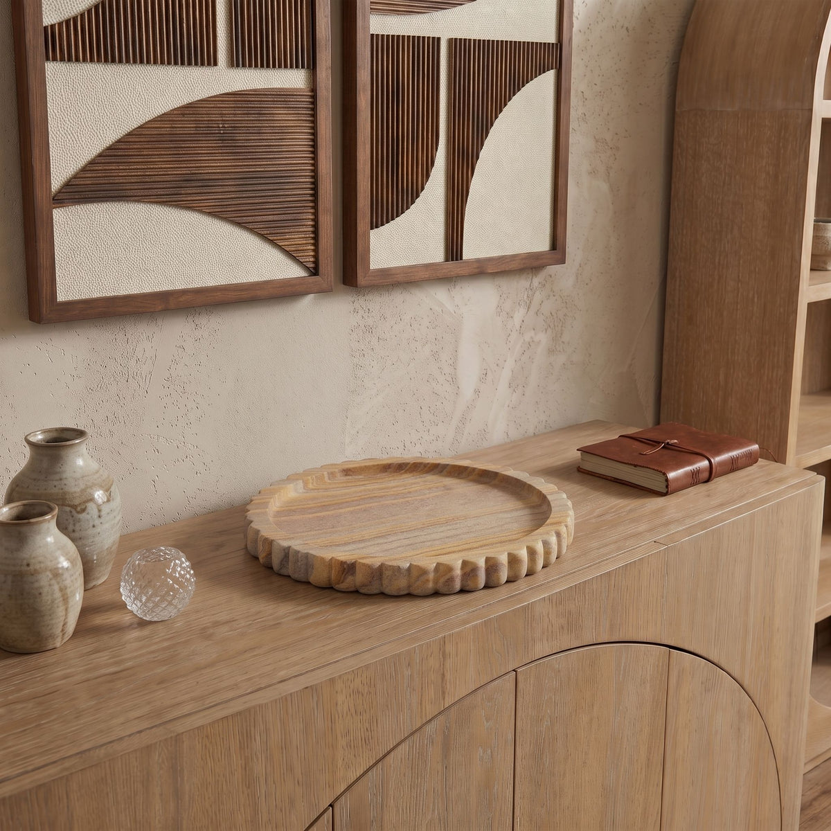 Round sandstone tray with scalloped edge displayed on a wooden shelf