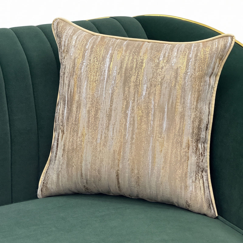 Beige and gold patterned accent pillow against a dark green fluted sofa