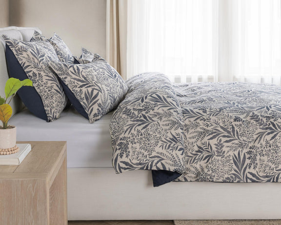 Denim blue leaf-pattern duvet set with layered pillow shams on a bed