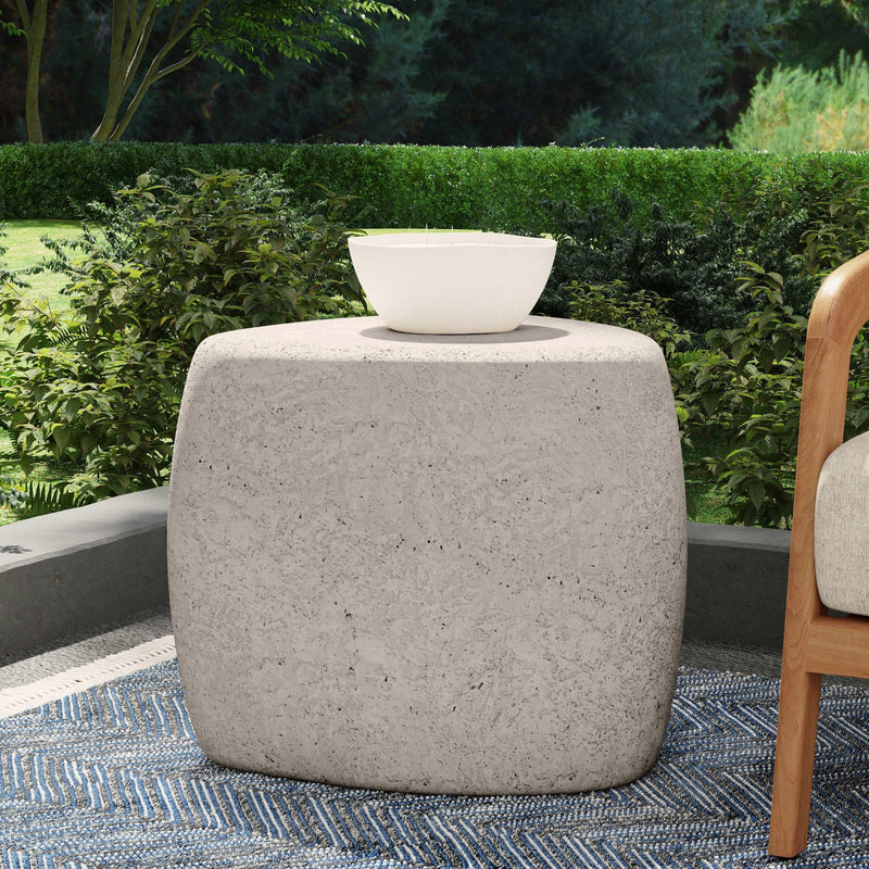 Round light gray outdoor end table with top opening holding a white planter bowl