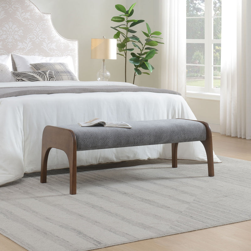 Gray upholstered bench with wooden legs beside the bed