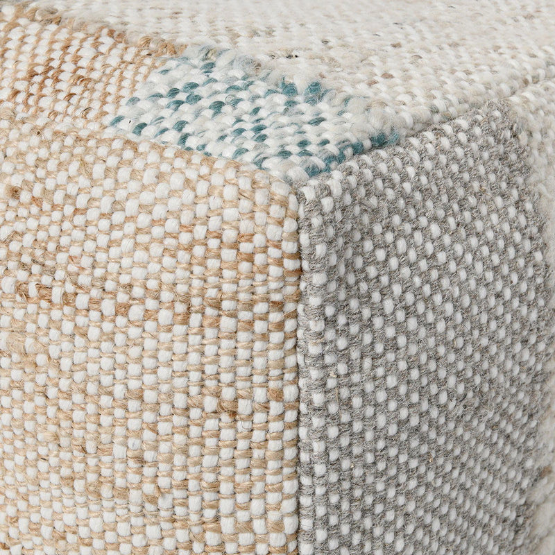 Textured woven ottoman pouf corner with visible stitching and light multicolor flecks