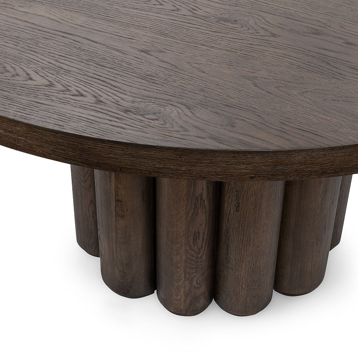 Toasted brown round dining table close-up of tabletop edge and fluted legs.