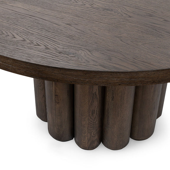 Toasted brown round dining table close-up of tabletop edge and fluted legs.
