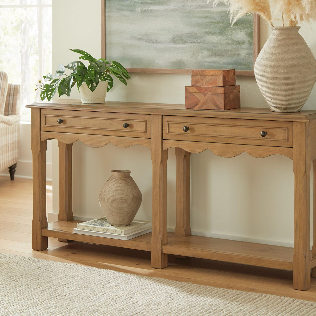 Light brown console table with drawers and scalloped apron, styled with vase