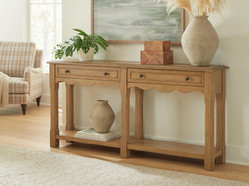 Light brown console table with drawers and scalloped apron, styled with vase
