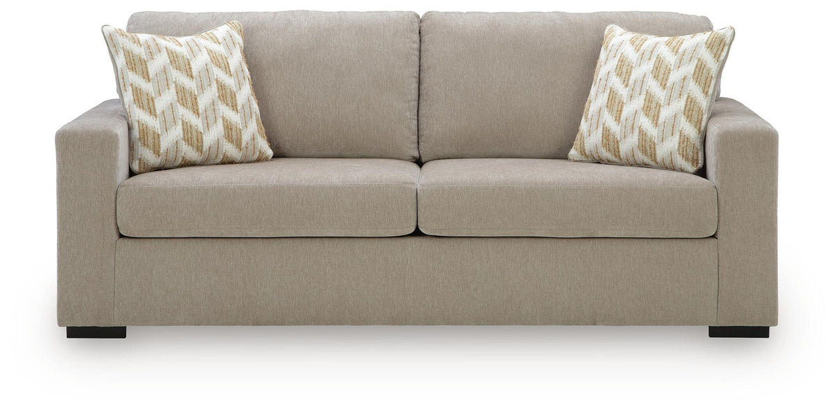 Beige fabric sofa with tufted back, two seat cushions, and patterned accent pillows