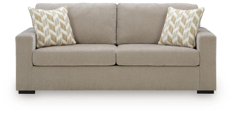 Beige fabric sofa with tufted back, two seat cushions, and patterned accent pillows