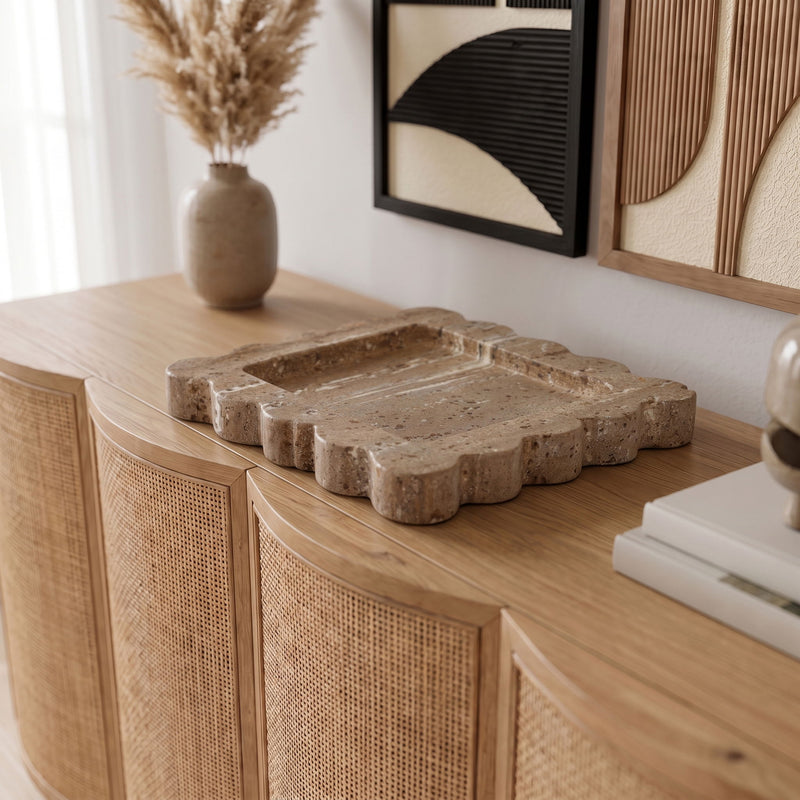 Natalie travertine tray on surface; beige speckled stone with scalloped rim and recessed well.