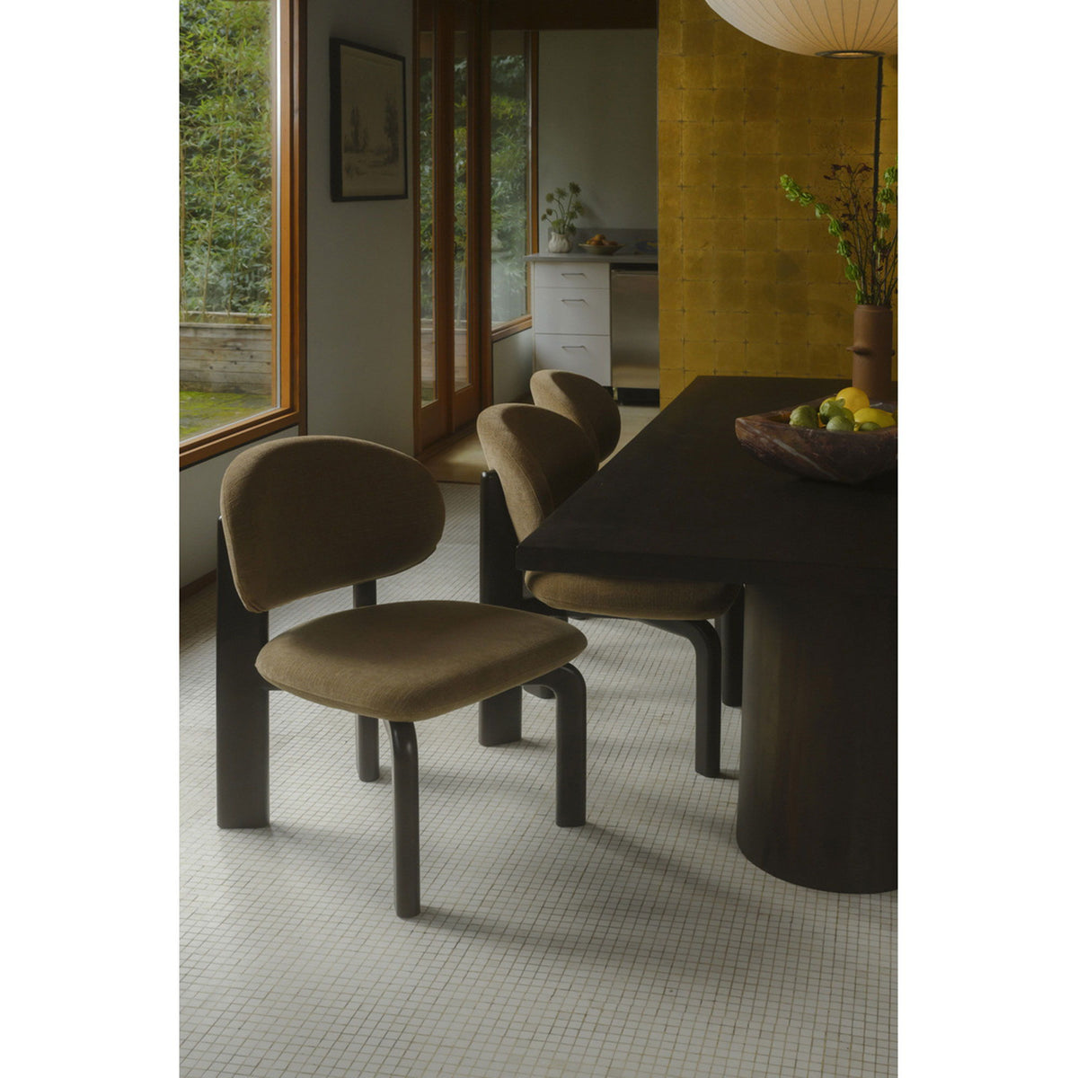 Tan dining chair with rounded back and dark brown legs, shown near table