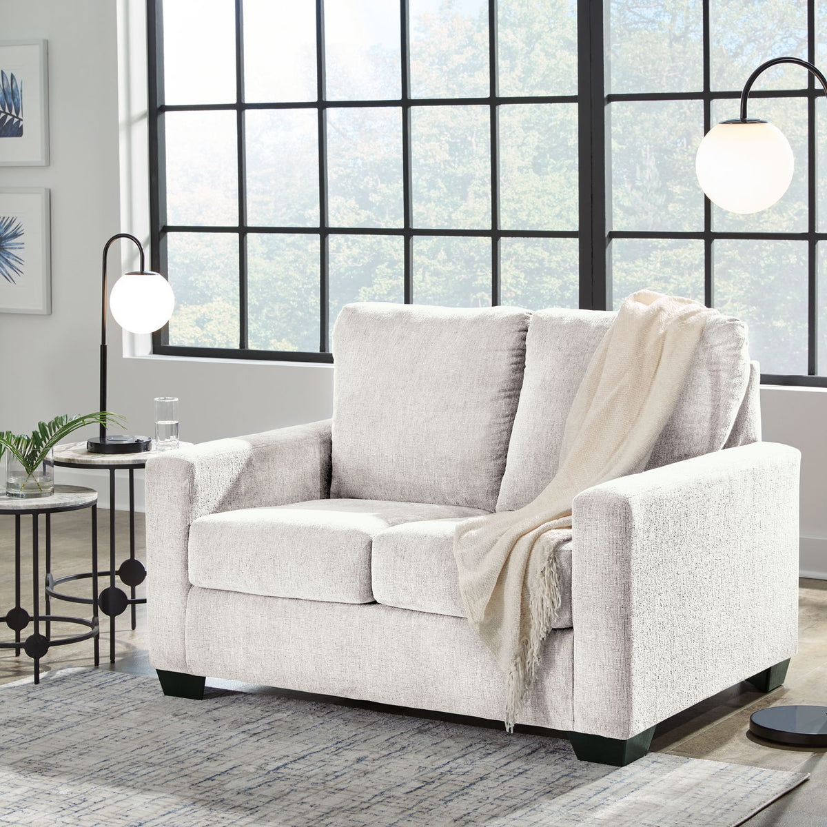 Beige fabric sofa with three back cushions, square arms, and a light throw draped