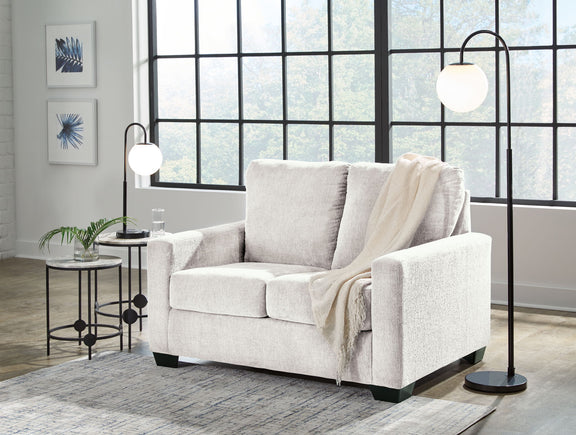 Beige fabric sofa with three back cushions, square arms, and a light throw draped
