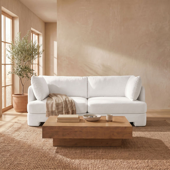 White velvet upholstered loveseat with rounded arms, two seat cushions, and back pillows