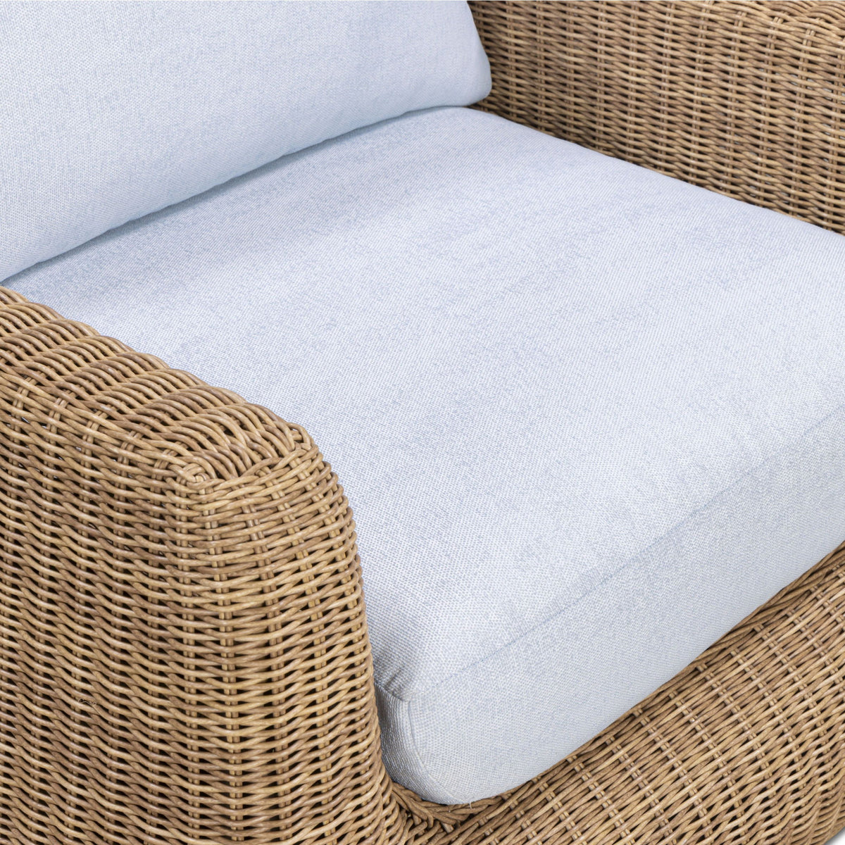 Outdoor accent chair close-up: light blue seat cushion and woven wicker arm