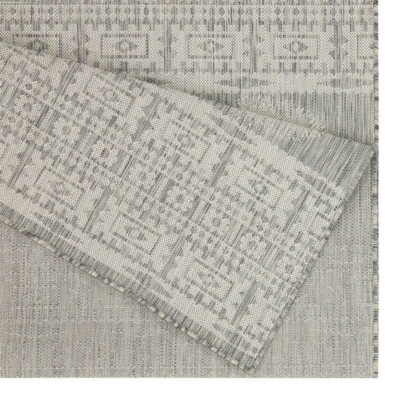 Light gray polypropylene area rug with geometric pattern and stitched fringe border