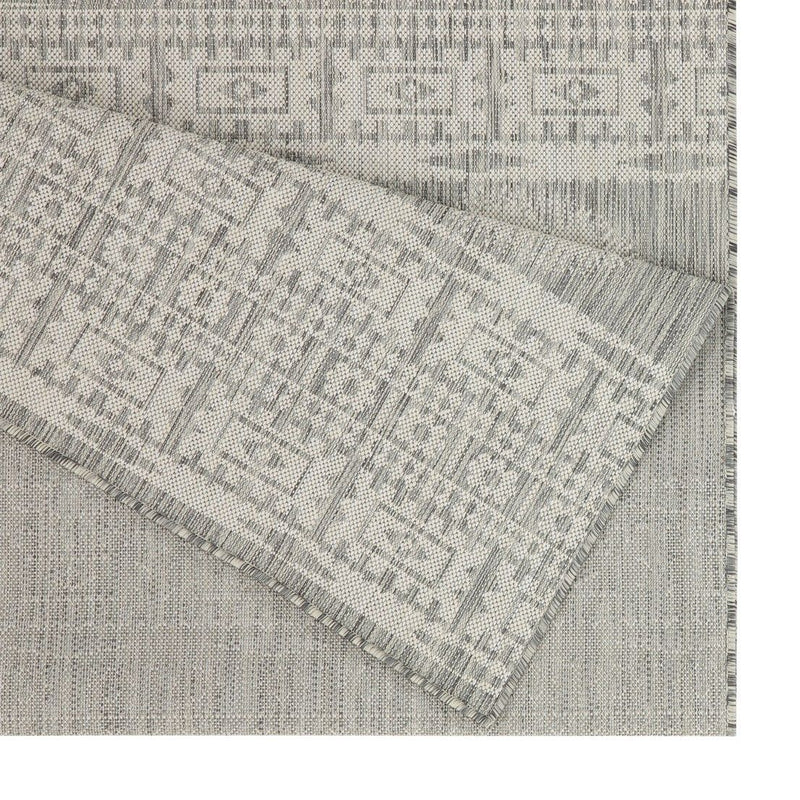Light gray polypropylene area rug with geometric pattern and stitched fringe border
