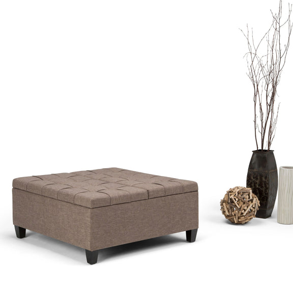 Taupe upholstered storage ottoman coffee table with tufted top and dark wooden legs