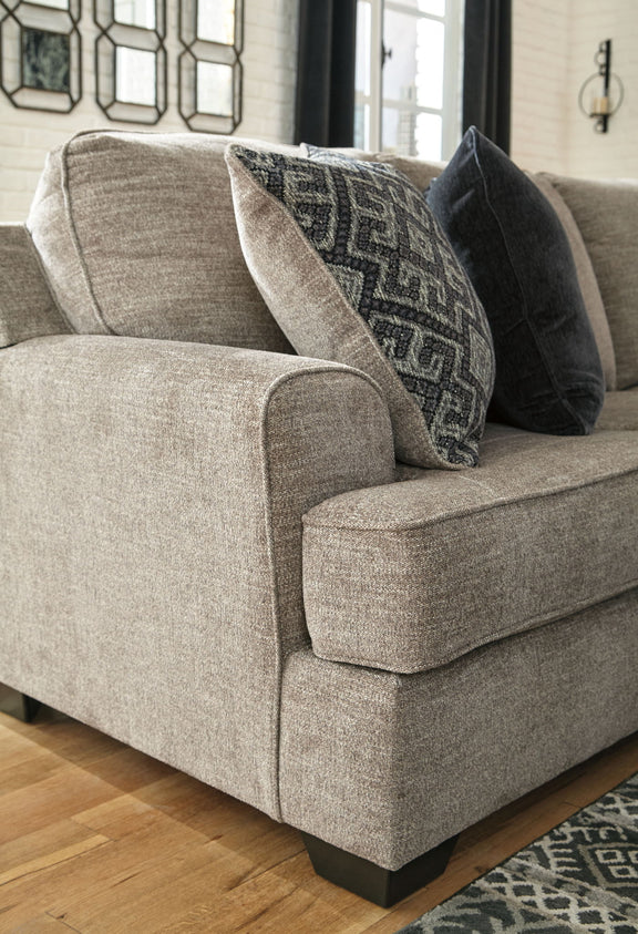 Beige sectional sofa arm with dark patterned and solid throw pillows