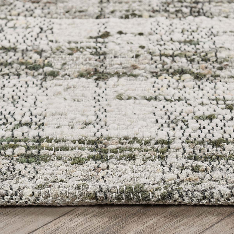 Speckled light gray rug close-up with green flecks and short fringed border