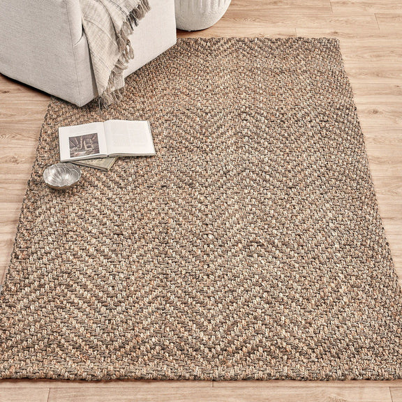 Jute herringbone rug with textured chevron weave in natural beige and light speckling.