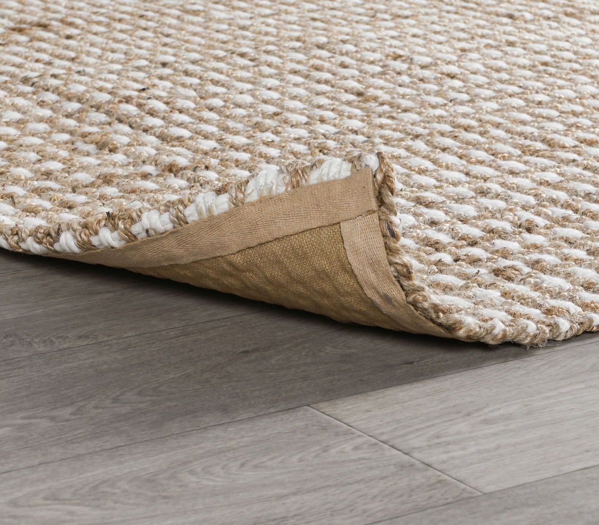 Natural rug corner detail with woven surface edge and protective backing