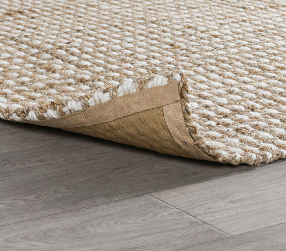 Natural rug corner detail with woven surface edge and protective backing