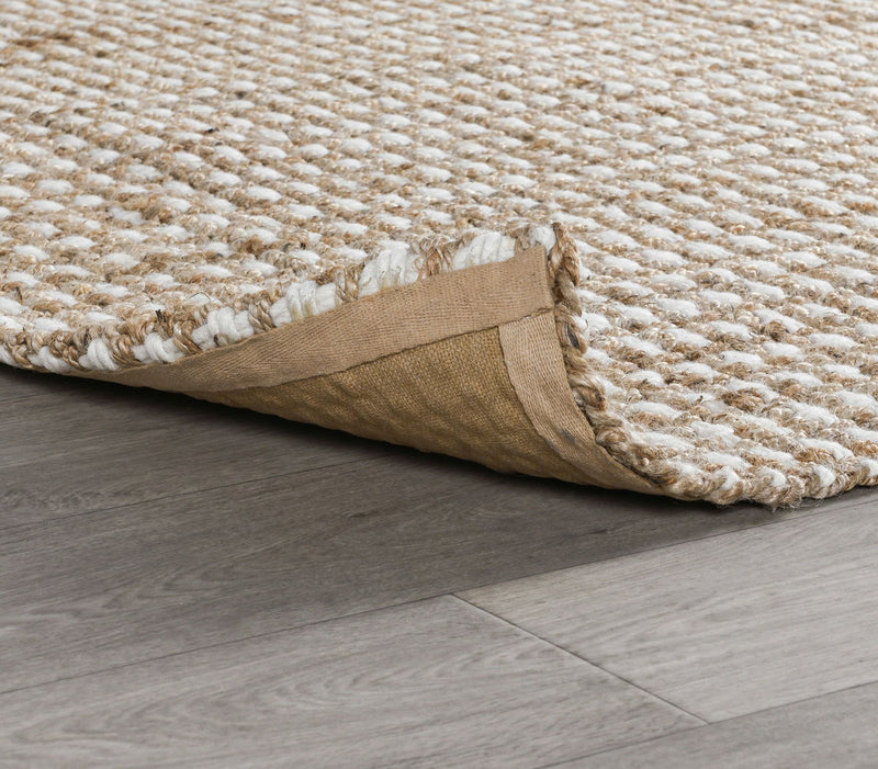Natural rug corner detail with woven surface edge and protective backing