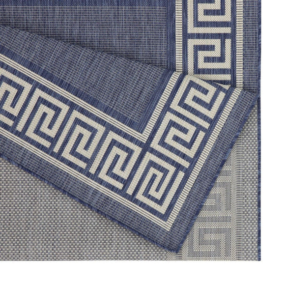 Close-up dark blue rug corner with white Greek key pattern and textured polypropylene weave