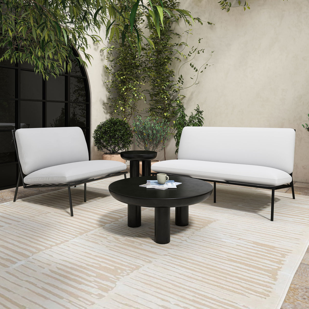 Round black cement coffee table with wide tabletop and central three-leg base