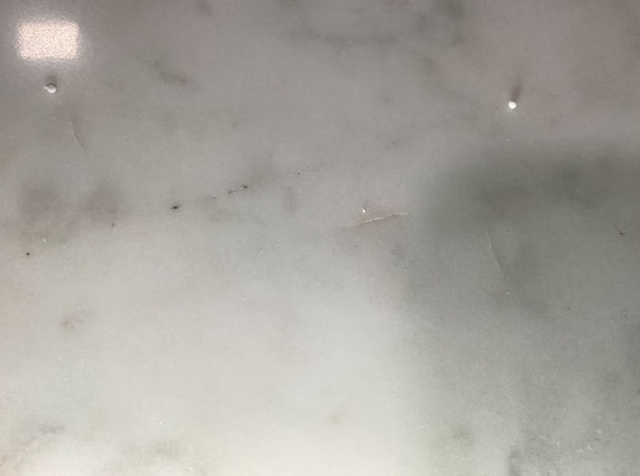 Close-up of white marble tabletop surface with faint gray speckling
