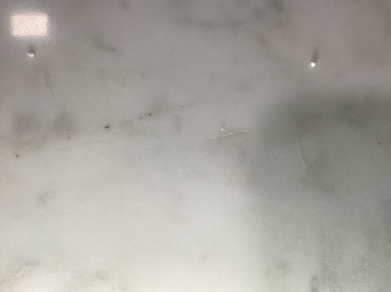 Close-up of white marble tabletop surface with faint gray speckling