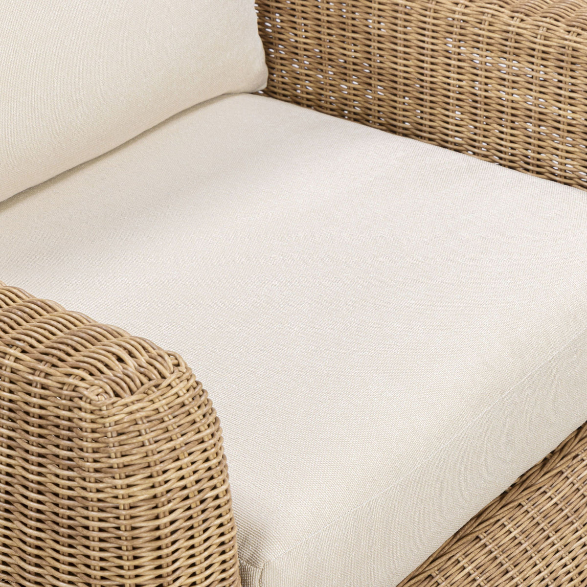 Outdoor accent chair close-up: white seat cushion with woven wicker arms